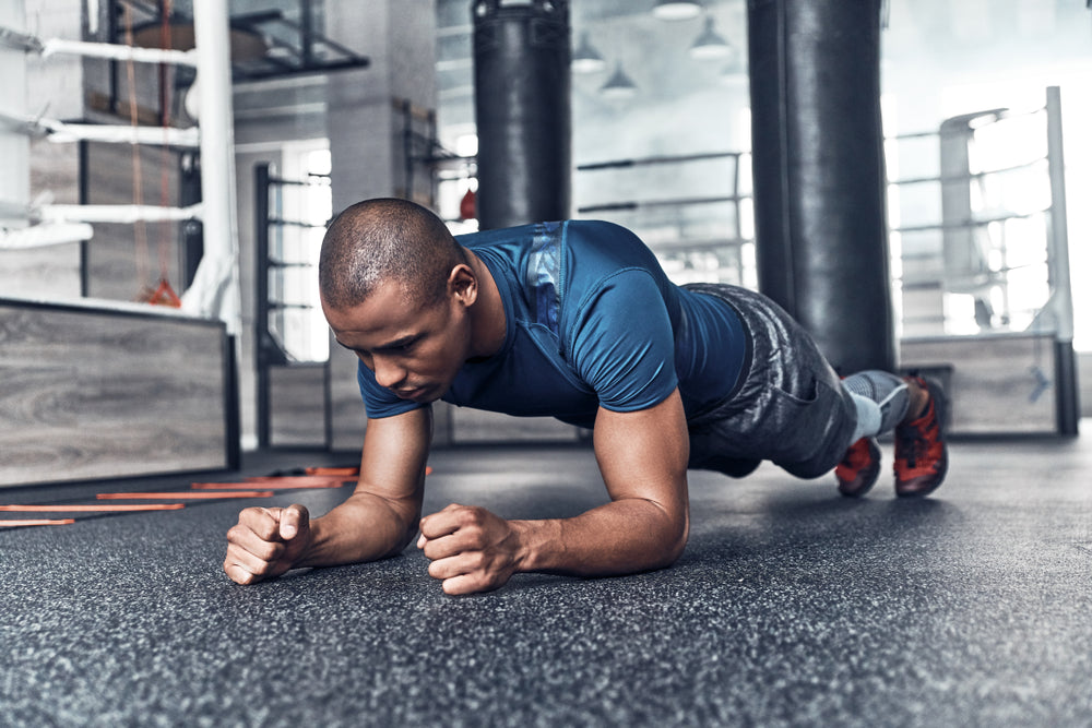fit you man in sporty clothing doing forearm plank in gym