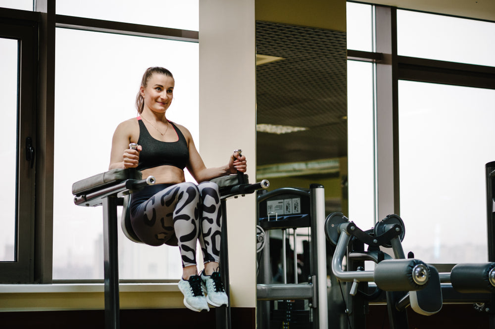 Young fitness woman doing captains chair leg raises