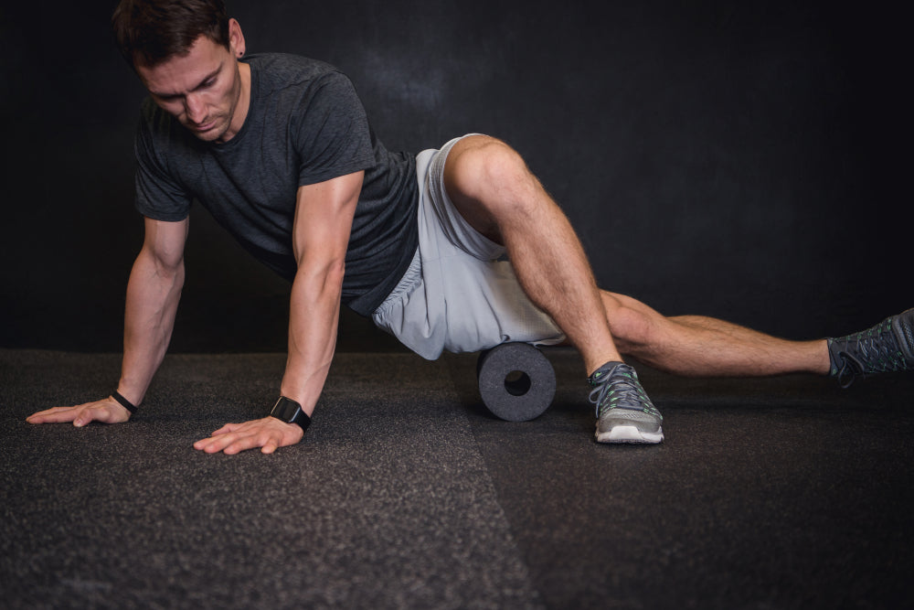 Athletic man using a foam roller to relieve sore muscles after a workout