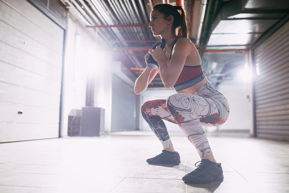 Young muscular woman doing goblet squat with kettlebell