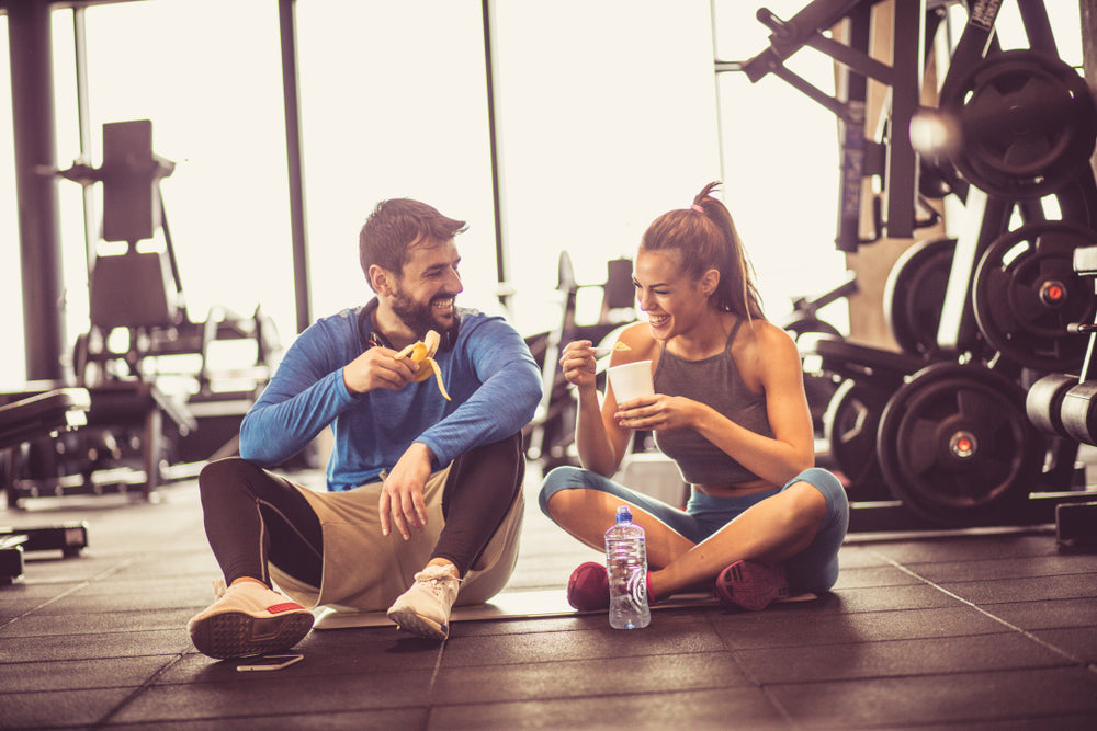 Young couple at gym eating healthy food after exercise.