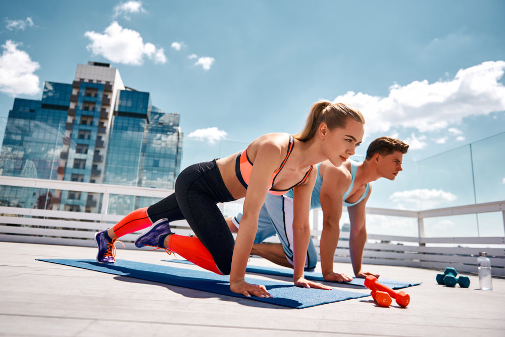 Strong man and woman are doing climber exercise while staying in plank position.