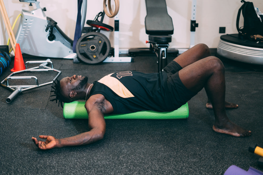 strong man Doing an Exercise with Foam Roller on his Upper Back 
