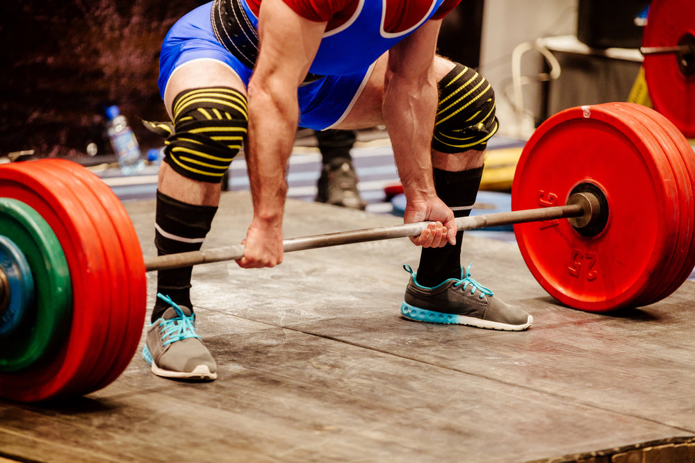 powerlifter wearing knee wraps while deadlifting