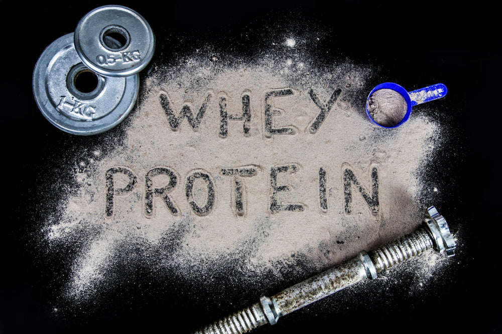 whey protein powder on black background with dumbbell