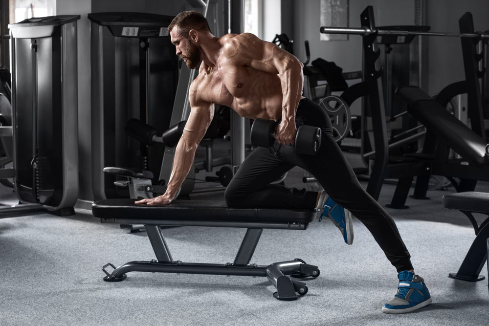 Muscular man workout in gym doing exercises for back. Single Arm Dumbbell Row