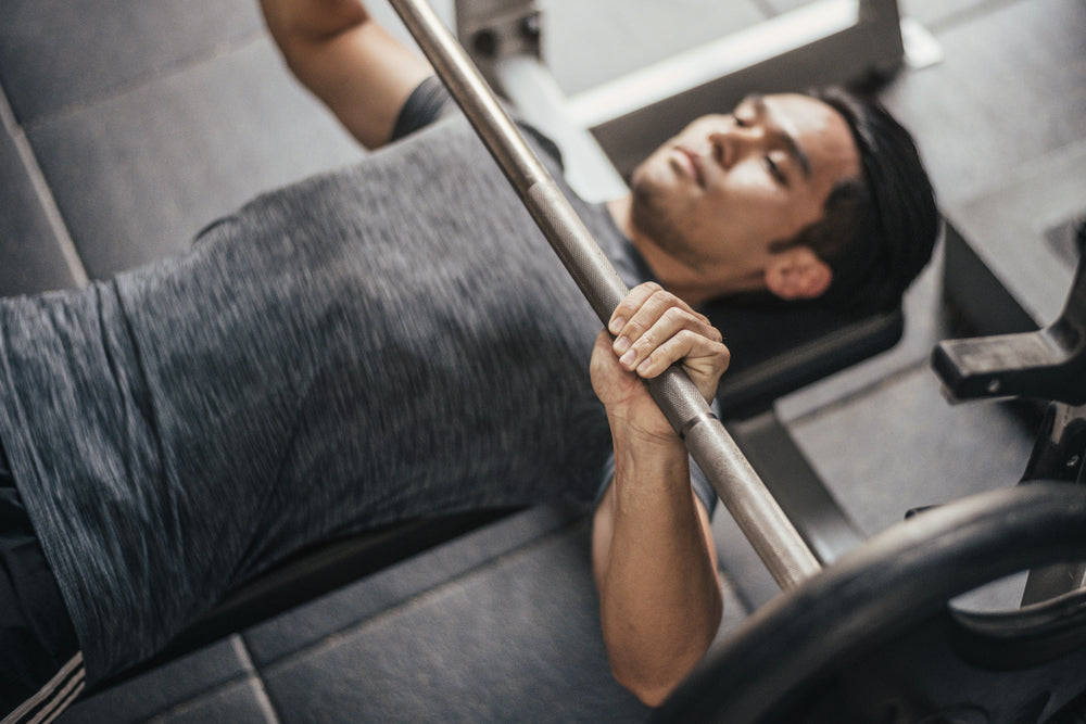 Close up hand grip barbell bench press in gym.