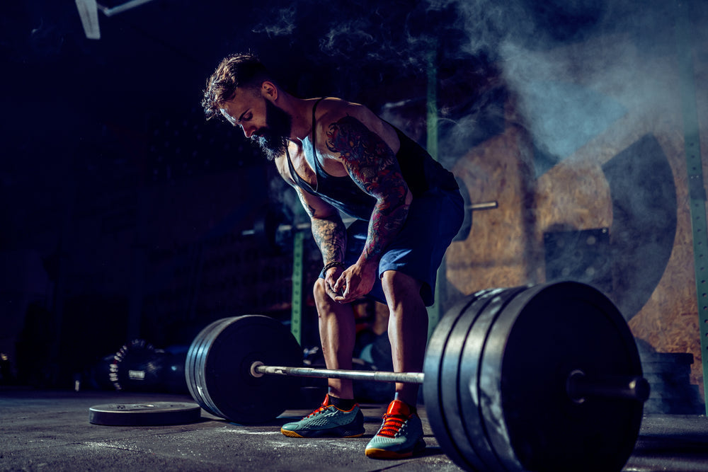 uscular fitness man preparing to deadlift a barbell in modern fitness center