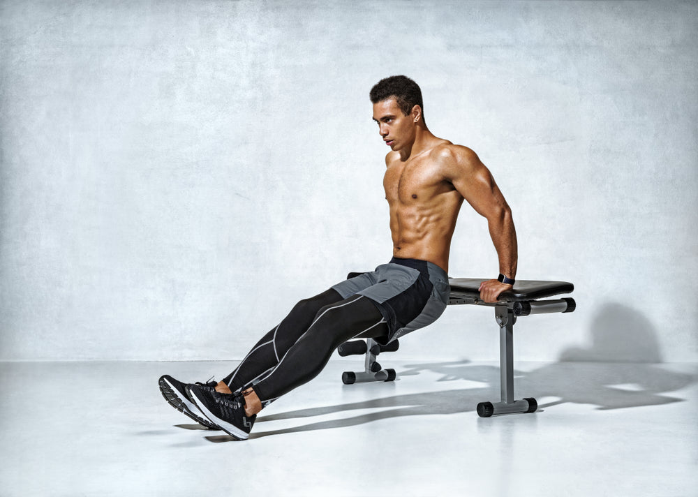 Strong man working out arms muscles doing triceps dips using bench