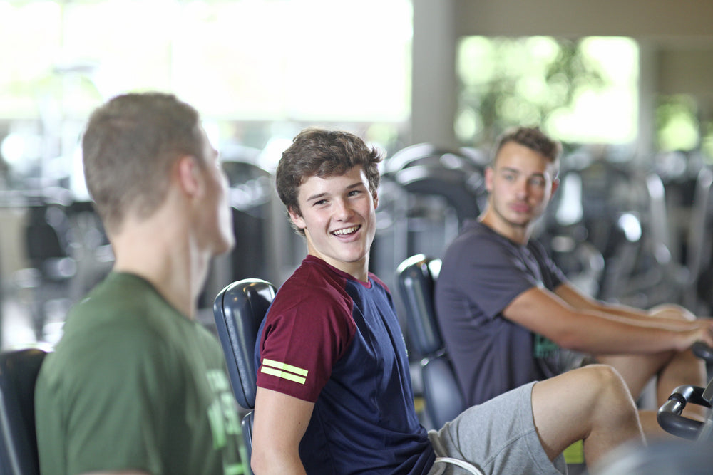 Teenage boys training on exercise bikes in gym