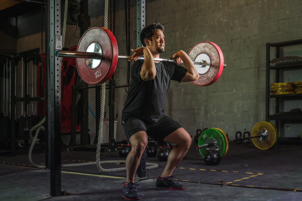 strong athletic man doing barbell front squat in gym