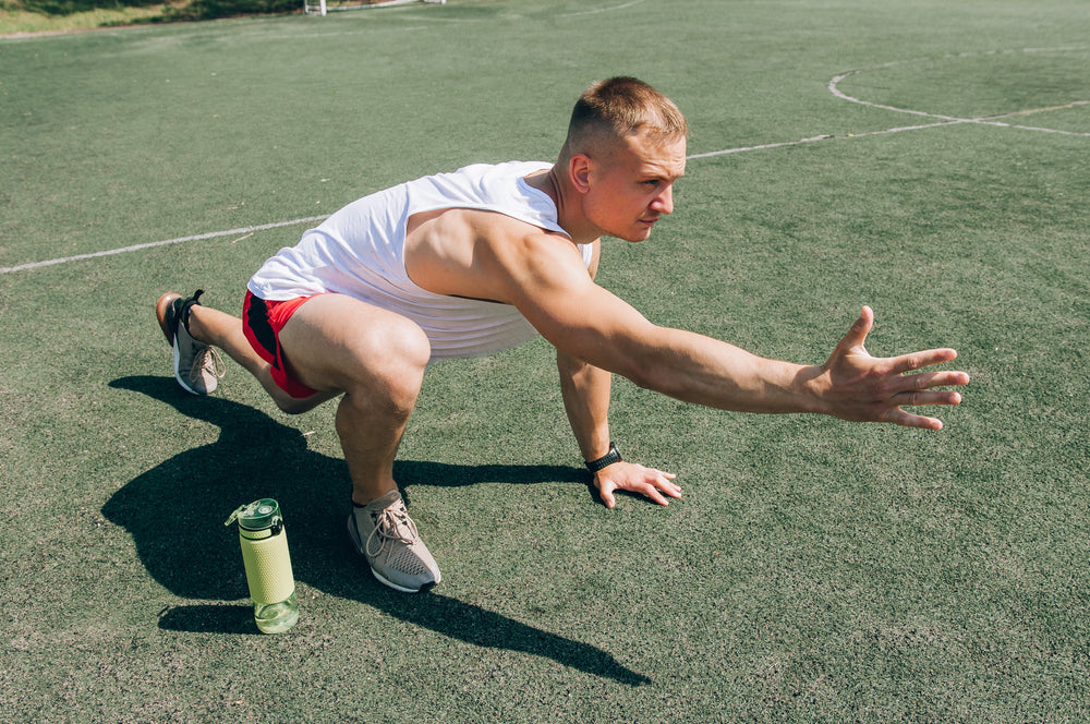 Runner man getting ready to run doing warm-up dynamic leg stretch exercises routine