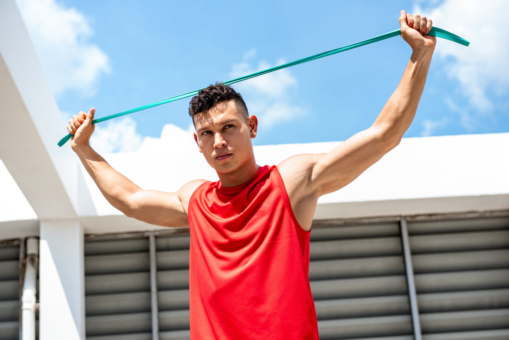 Handsome athletic man stretching with resistance band outdoors on building rooftop, home exercise concept A  By Atstock Productions  Asset data