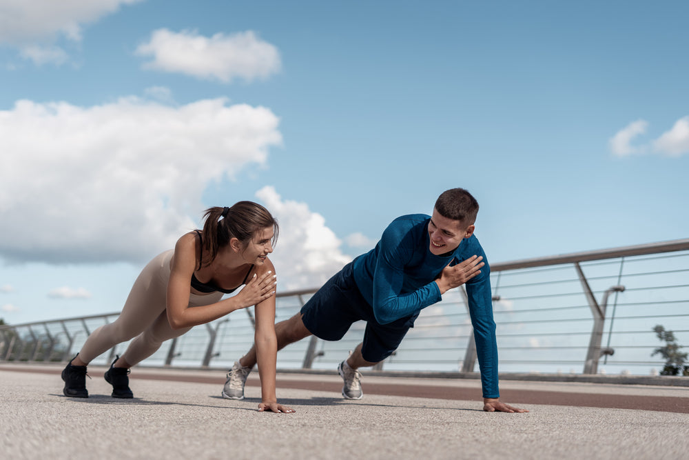 athlete woman and man doing shoulder tap exercise outdoors