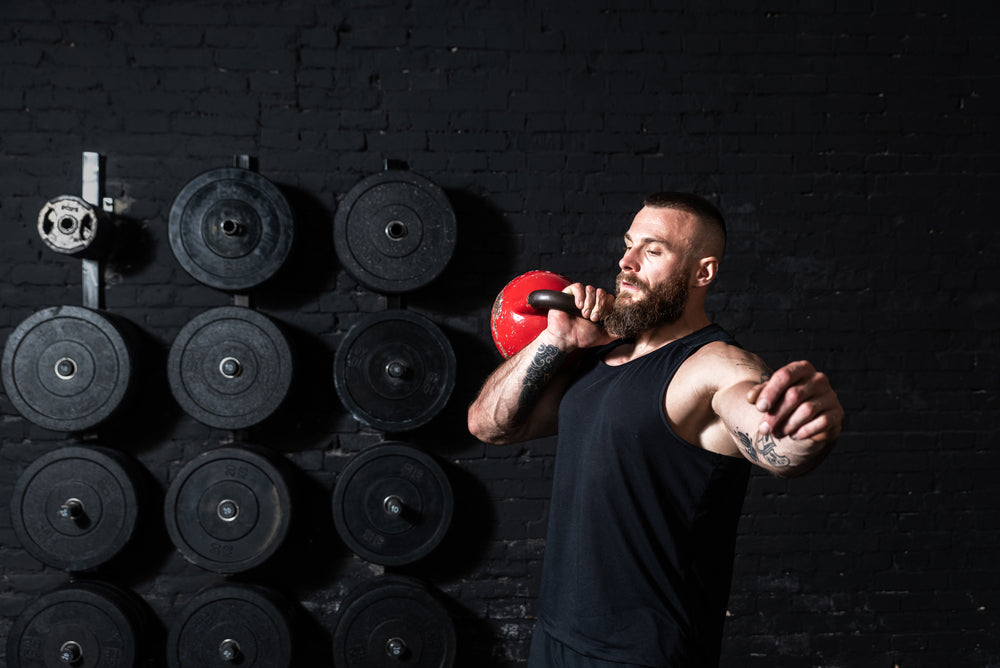 Young sweaty strong muscular fit man with big muscles doing kettlebell snatch