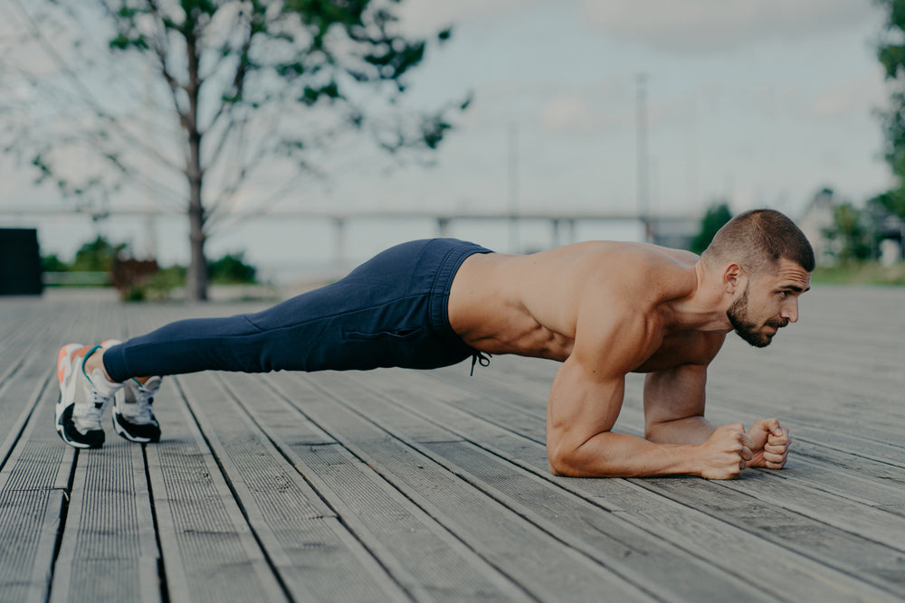 male athlete doing a plank outdoors