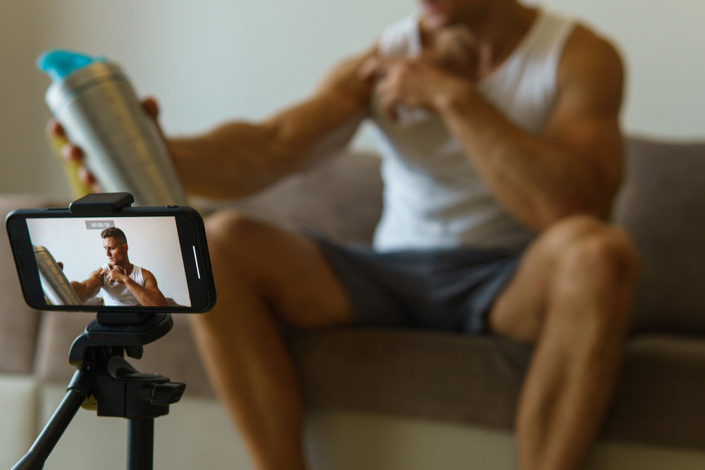 Fitness blogger is streaming or recording video for his subscribers during his home workout