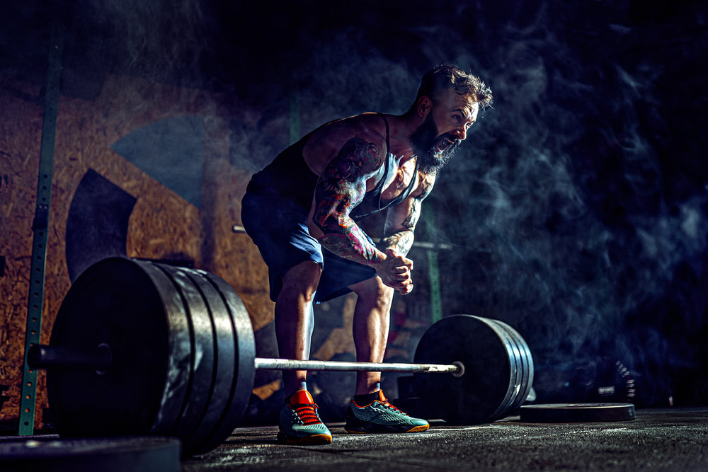 Muscular fitness man preparing to deadlift a barbell in modern fitness center