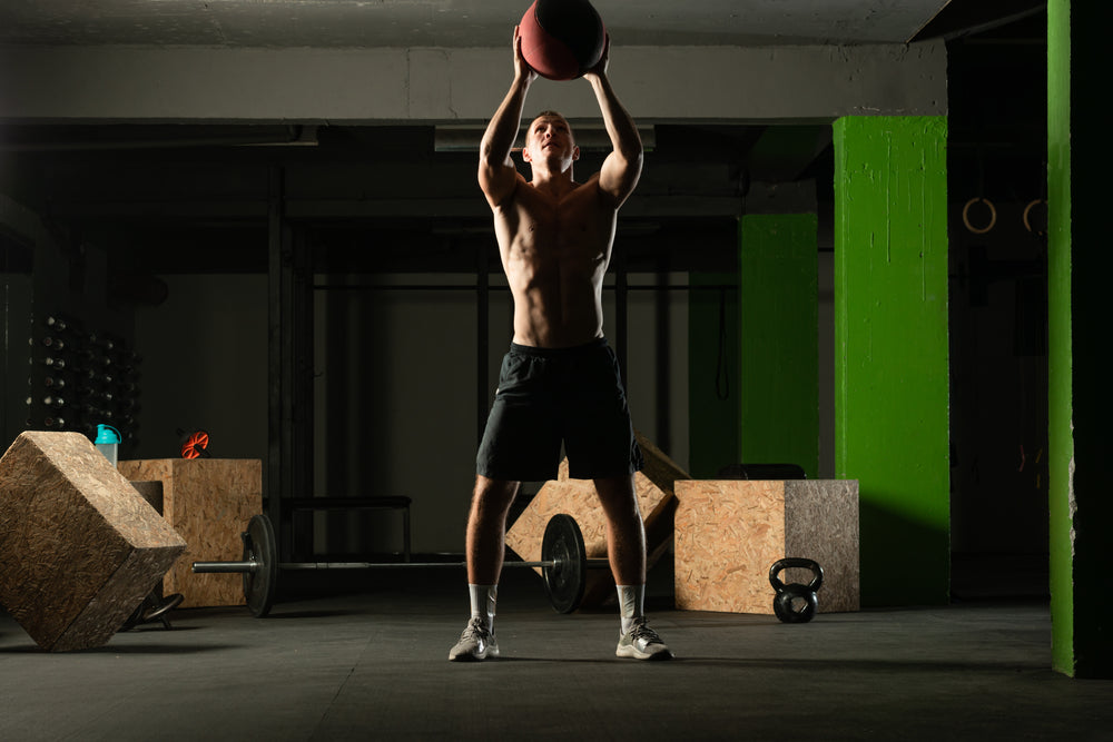 Fit man throwing medicine ball doing ball slam against gym floor