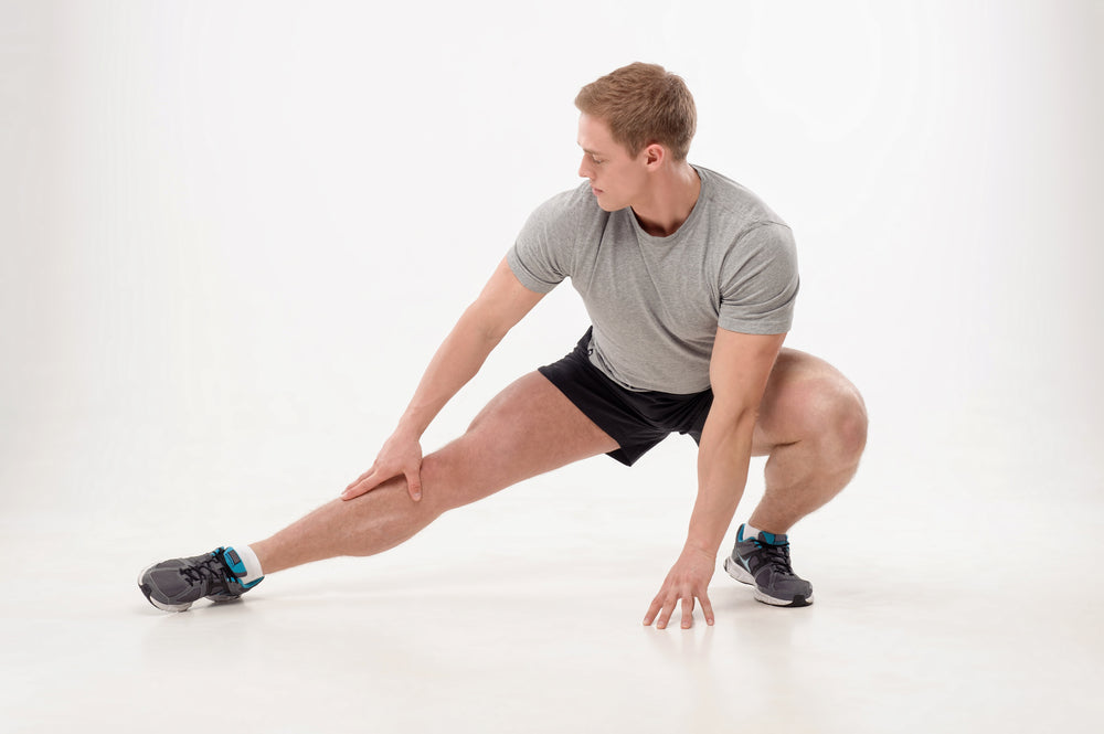 Full length portrait of young smiling man athlete doing warming exercises isolated on white background