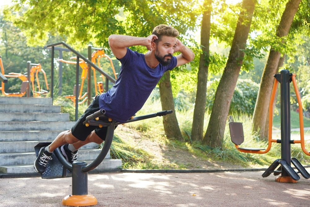 Fit man training on the hyperextension bench at the city park.