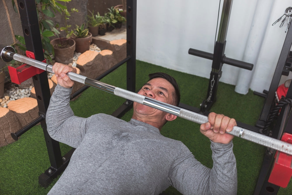 A fit asian guy performs a set of bodyweight inverted rows