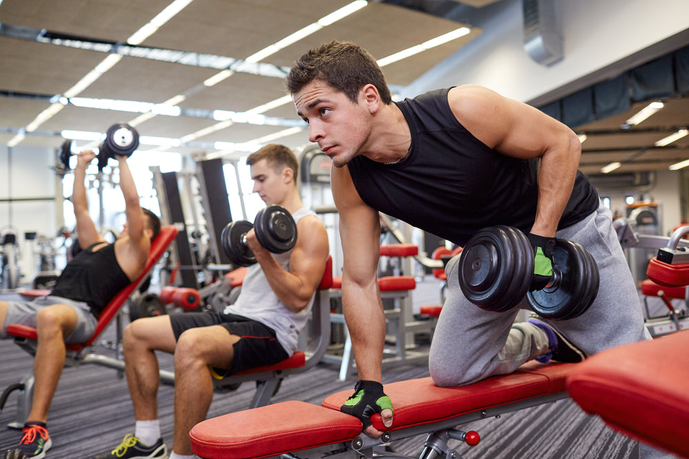 group of men flexing muscles with dumbbells in gym