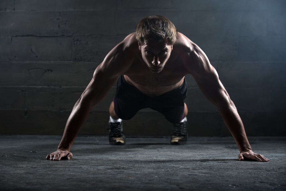 Athlete with a beautiful body and a naked torso doing push-ups exercise on the floor.