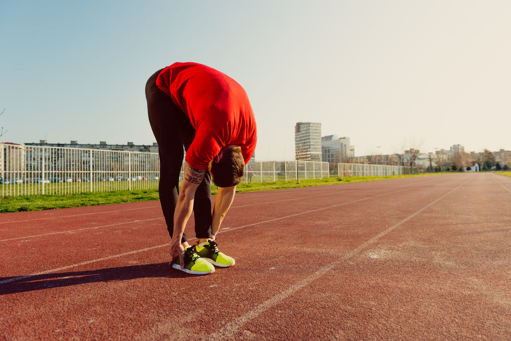 Athlete warming up and touching his toes on a running track