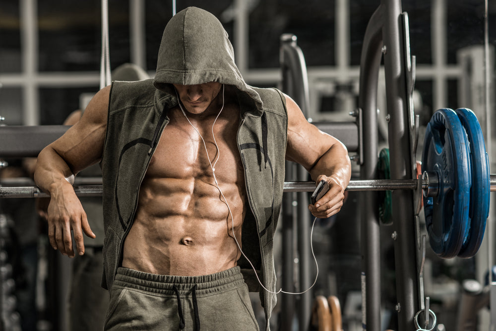 bodybuilder in gym listening to music on phone with headset 
