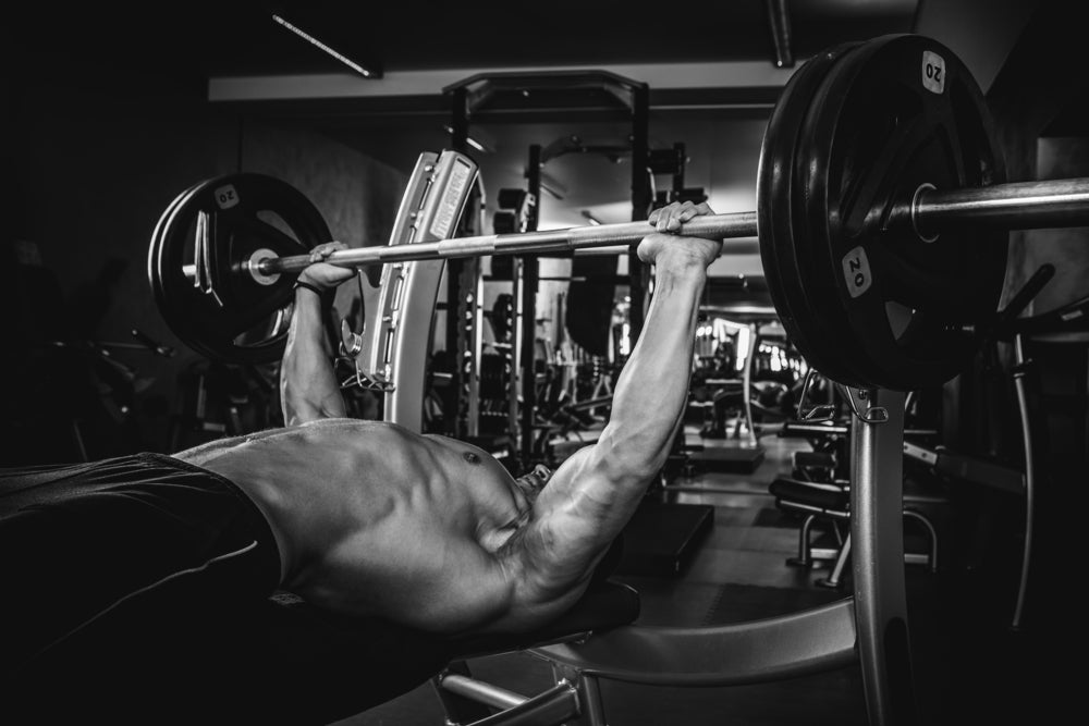 athletic man pumping up muscles on bench press