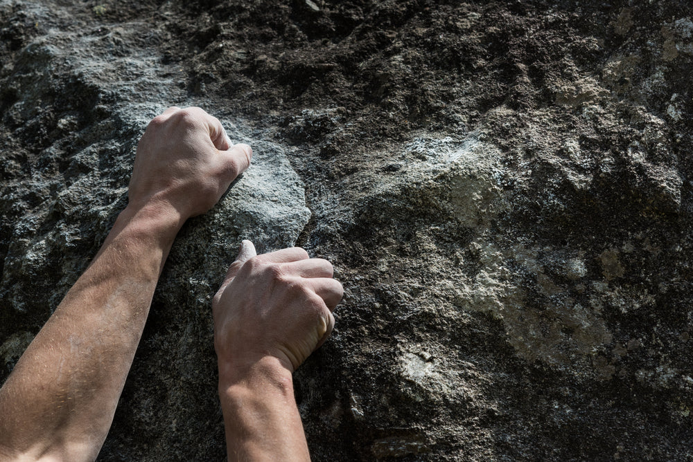Two hands of rock-climber gripping a rock ledge during a bouldering