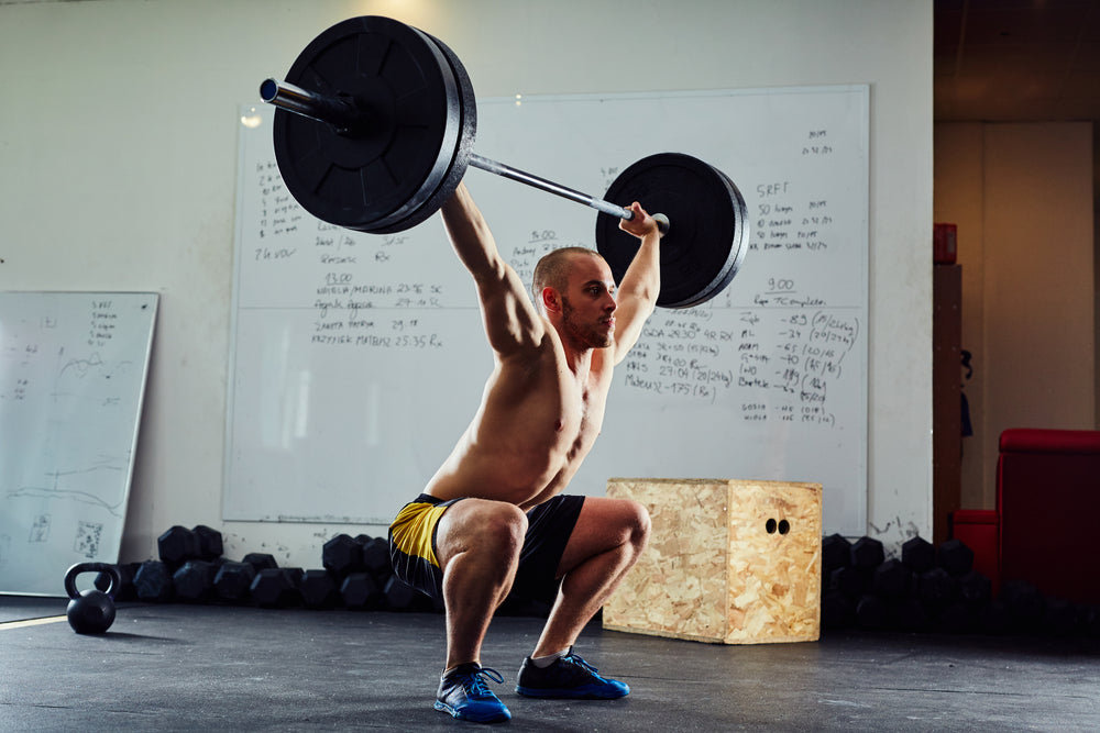 young man doing barbell snatch exercise in a gym