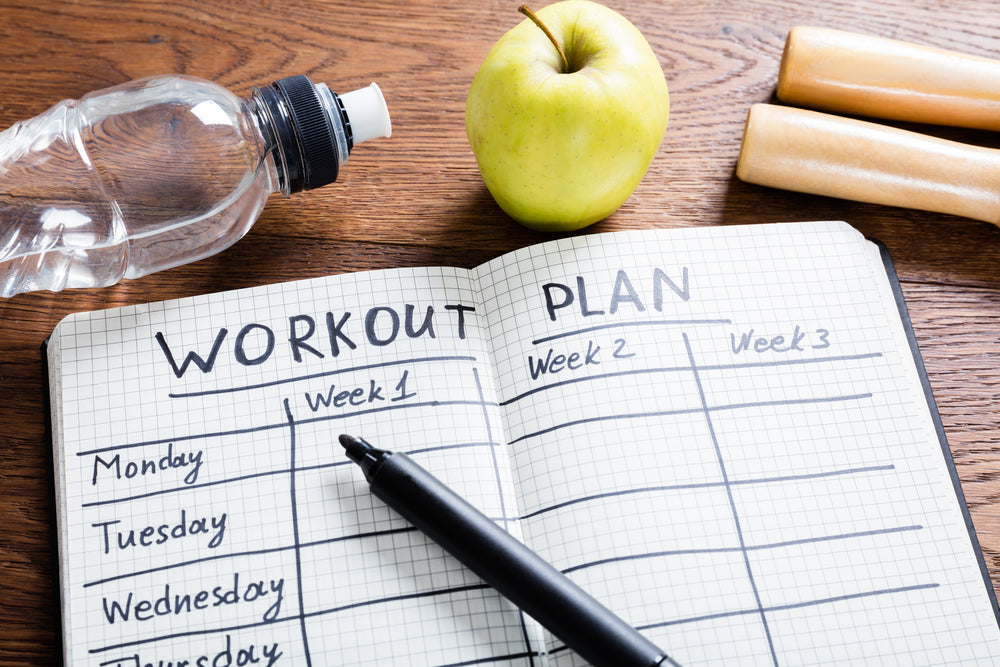 High Angle View Of A Workout Plan In Notebook At Wooden Desk
