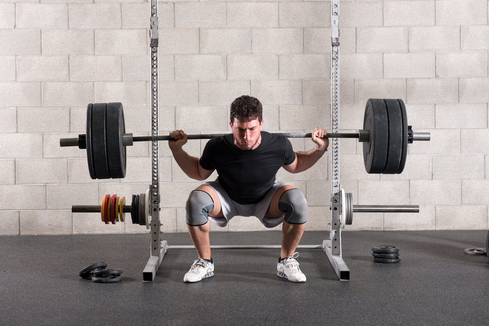 Man doing barbell back squats in a gym