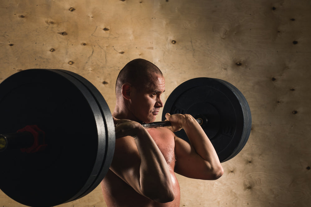 strong man doing hang clean with a barbell in a gym
