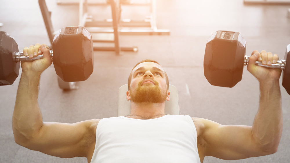 bodybuilder does bench press using dumbbells at the gym