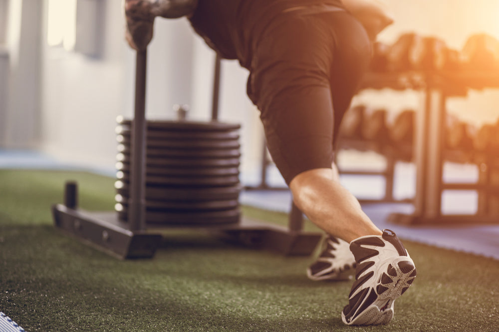sled push man pushing weights workout exercise at gym