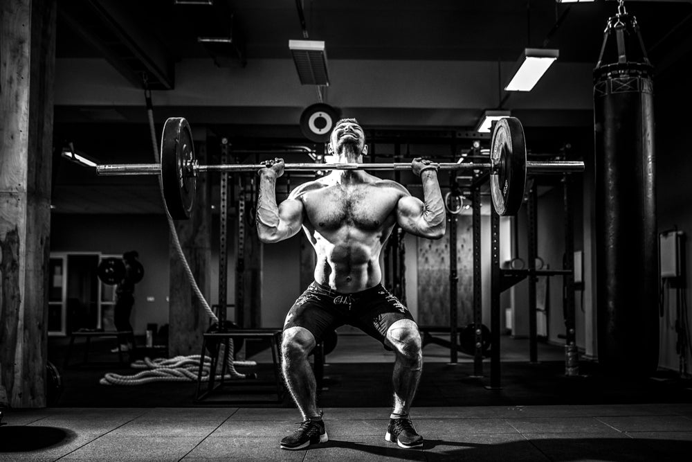 Muscular fitness man doing a barbell clean in a gym