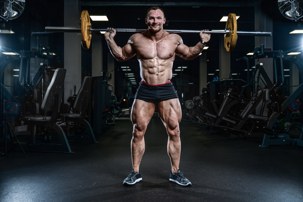 bodybuilder working out in the gym training legs quadriceps and hamstrings on machines and with a barbell