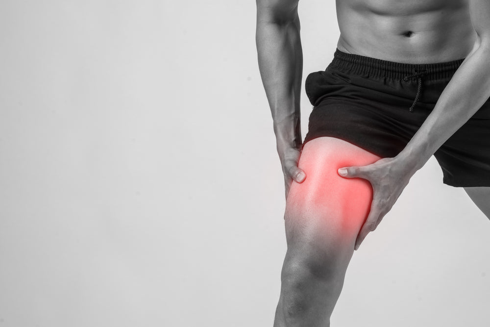 Young sport man with strong athletic legs holding knee with his hands in pain
