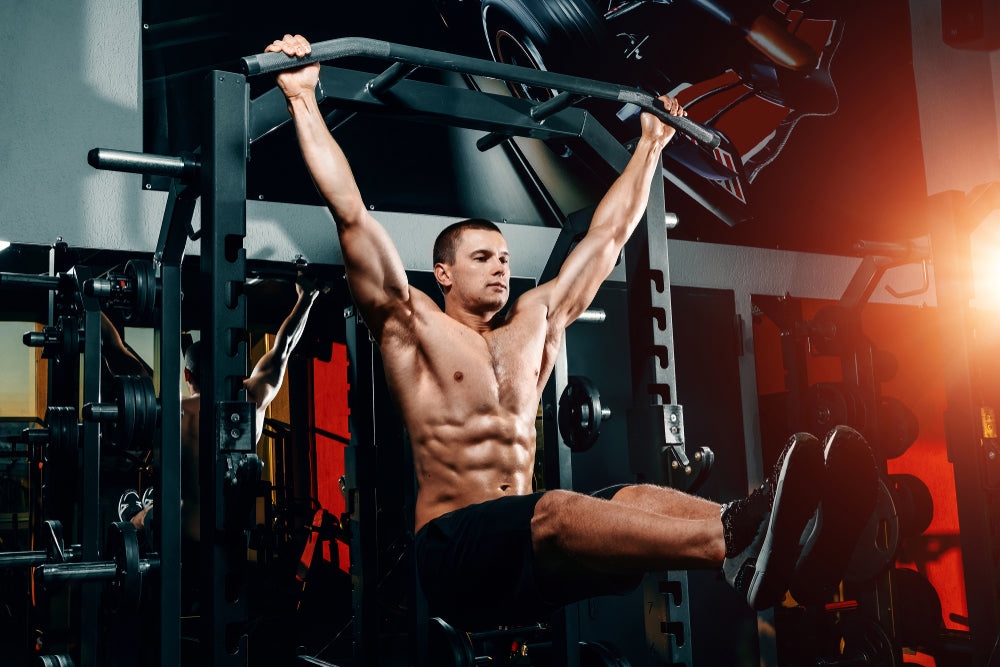 strong muscular man doing hanging leg raises in a gym