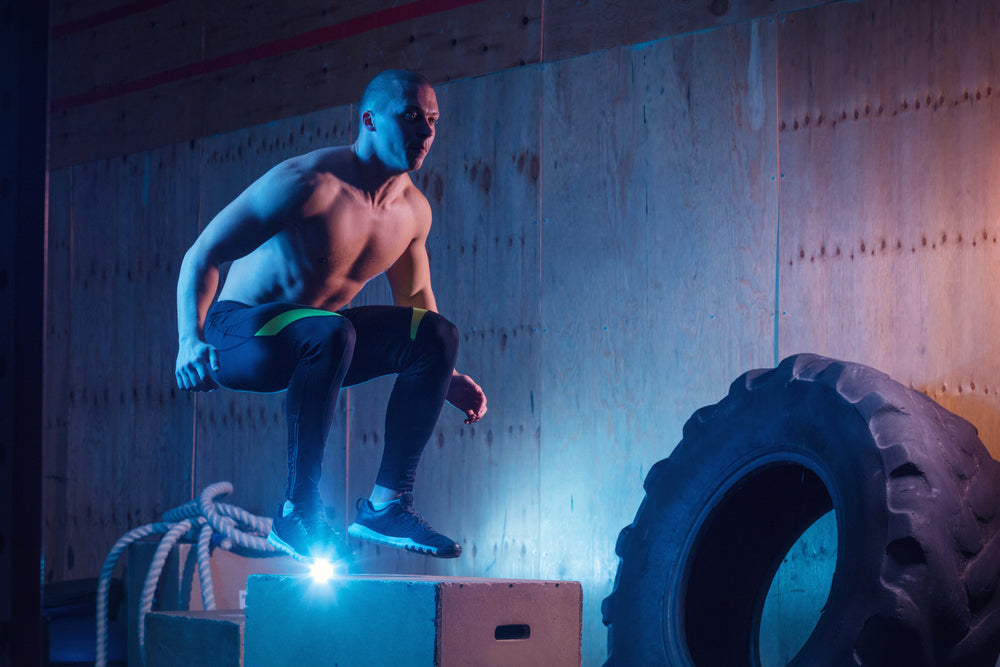 Athletic man jumping on fit box in gym